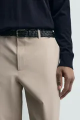 Pantalón de corte regular fit, color negro, confeccionado en tejido elástico. Presenta cintura elástica, cierre frontal con cremallera y botón, bolsillos laterales y bolsillos traseros de vivo.