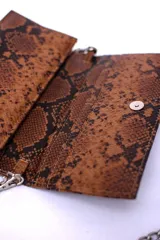 Cartera negra con textura símil cocodrilo y cadena metálica plateada.