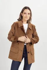 Chaqueta de gamuza color tostado con cuello camisero, cierre frontal de botones y bolsillos delanteros con solapa.