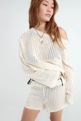 Sweater de manga larga y tejido calado color beige, con cuello redondo y diseño liviano.