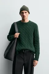 Jersey de punto con diseño de trenzas verticales, cuello redondo y manga larga. Presenta un ajuste regular y acabados en rib en cuello, puños y ruedo.