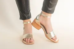 Sandalias doradas de cuero con pulsera al tobillo y taco de madera.