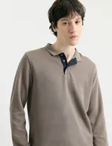 Remera de manga larga con cuello polo, confeccionada en tejido de punto canalé francés. Presenta abotonadura frontal con botones de madera y detalles a contratono en la cartera y el interior del cuello.