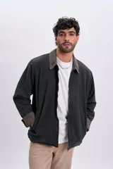 Campera gris oscuro de lona, con cuello camisero de pana en tono contrastante y cierre frontal con cremallera metálica.