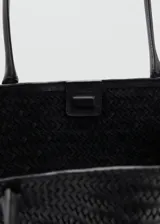 Bolso tipo tote negro confeccionado en cuero con diseño trenzado, asas largas para el hombro y cierre de botón magnético.
