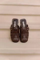 Suecos de cuero vacuno color marrón, marca Amén, con diseño de tiras entrelazadas, puntera cuadrada y hebilla metálica ajustable en el lateral.