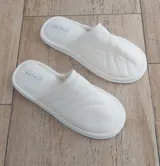 Pantuflas bajas de algodón color blanco, con diseño acolchado y suela plana.