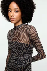 Vestido largo de tul con estampado animal print tipo cebra, cuello alto, mangas largas y detalle fruncido en la cintura.