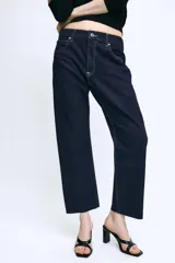 Jeans de tiro medio confeccionados en denim azul oscuro, con diseño de cinco bolsillos, trabillas para cinturón y bajo deshilachado. Cierre frontal con cremallera y botón metálico.
