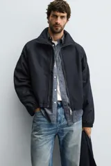 Cazadora de corte cropped confeccionada en tejido de algodón con ligero acolchado interior. Presenta cuello subido, cierre frontal con cremallera, mangas largas con puños elásticos y bolsillos laterales de vivo.