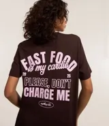 Remera de algodón color marrón con cuello redondo y mangas cortas. Presenta estampa con la frase "Fast Food is my candy" en color rosa.