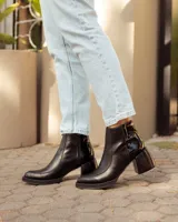 Botas de cuero negras con punta cuadrada, tacón ancho y detalles de textura en relieve en la parte superior.