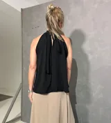 Musculosa negra sin mangas con cuello halter fruncido, confeccionada en tejido liviano de caída fluida.