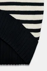 Chaleco de punto amplio con diseño a rayas horizontales en blanco y negro, de cuello redondo, manga sisa y bajo asimétrico con acabados en rib.