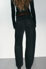 Jeans de mezclilla en color negro gastado, tiro alto, diseño de cinco bolsillos y corte de pierna ancha extra larga. Cuenta con cierre frontal de cremallera y botón metálico.
