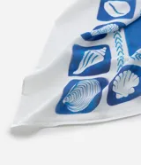 Canga rectangular de viscosa certificada, con estampado en tonos blanco y azul que incluye motivos de caracolas y patrones geométricos en el borde.