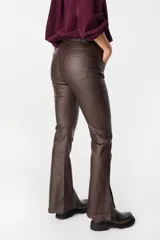 Pantalón de ecocuero color marrón, de corte recto con terminación ligeramente acampanada y tajos frontales en el ruedo. Cuenta con cierre y botón frontal, además de bolsillos laterales y traseros.