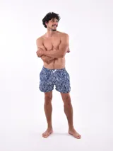 Short de baño blanco con estampado de hojas en tonos azules y rosados, cintura elástica con cordón ajustable.