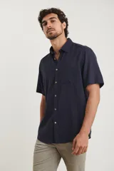 Camisa sport de manga corta, confeccionada en una mezcla de lino y algodón. Presenta cuello clásico, cierre frontal con botones de coco y un bolsillo aplicado en el pecho.