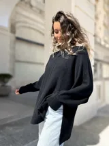 Sweater de punto color negro, con diseño oversize, cuello redondo, costura central vertical y aberturas laterales en el ruedo. Presenta mangas largas con puños acanalados.