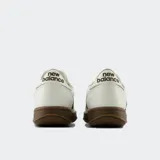 Championes urbanos New Balance modelo 500, con diseño de perfil bajo en color blanco, detalles en marrón oscuro en el logo lateral y suela de goma en tono marrón.