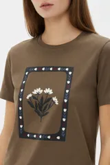 Remera de manga corta color azul marino con cuello redondo y estampado frontal de una flor en tonos celestes y blancos.