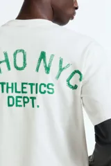 Remera de corte holgado en punto de algodón, con cuello redondo acanalado y hombros caídos. Presenta un estampado frontal con la inscripción Soho NYC Athletics Dept. en color verde.