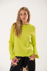 Blusa verde lima con textura arrugada, cuello redondo con volantes y mangas largas con puños elásticos.