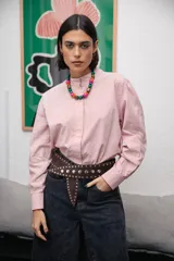 Camisa de corte clásico con cuello mao y cierre frontal oculto, confeccionada en tela de algodón con estampado de rayas verticales finas en color rojo y blanco. Presenta mangas largas con puños abotonados.