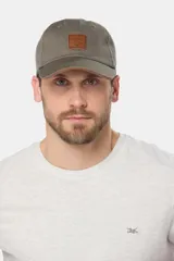 Gorro visera de lona verde militar con parche de cuero frontal y detalles marrones en la visera, de marca Legacy.