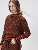 Sweater de tejido de punto jacquard con diseño geométrico, cuello redondo y puños acanalados en contraste de color verde y beige.