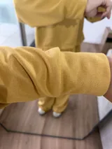 Conjunto de dos piezas compuesto por un buzo de cuello redondo y mangas largas con diseño reversible y un pantalón de corte ancho con cintura elástica.