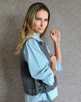 Chaleco de corte recto y largo a la cintura, confeccionado en denim con estampado de rayas verticales en tonos azul y blanco. Presenta cuello redondo y costuras visibles que definen su estructura.