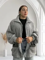 Camperón gris de tela tipo peluche con cierre frontal y bolsillos laterales.