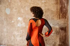 Vestido midi de jersey color naranja con estampado abstracto en negro. Tiene mangas largas abullonadas y escote redondo.