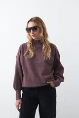 Polera gris de tejido suave de punto, con cuello alto, mangas abullonadas, puños elásticos y diseño relajado.