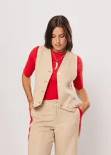 Chaleco beige con escote en V, sin mangas y cierre frontal con botones. Presenta pespuntes en color rojo y logo bordado en la espalda.