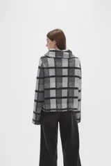 Sweater de tejido jacquard con diseño de cuadros, cuello solapa y cierre frontal parcial. Presenta un corte holgado y mangas largas.