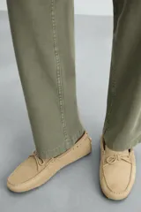 Mocasín casual de cuero color marrón claro con acabado serraje, horma redonda, detalle de lazo en el empeine y suela de goma.