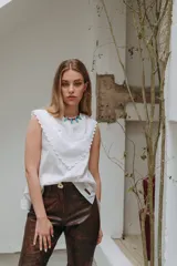 Musculosa blanca sin mangas con detalles de bordado inglés y apliques en el pecho.