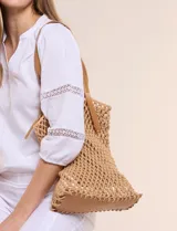 Cartera tipo shopper con estructura externa de tejido tipo red en color tostado, base sólida reforzada y correas dobles integradas de cuero sintético. Cuenta con compartimento principal interior con cierre.