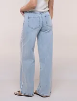 Pantalón jean de tiro alto y corte wide leg en color celeste, con detalle de puntilla en los laterales. Cuenta con cinco bolsillos, presillas para cinto y cierre frontal con botón.