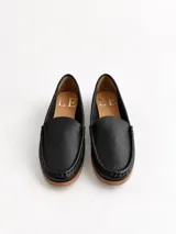 Mocasines de cuero color dorado con acabado texturizado, diseño clásico de punta redondeada y costuras visibles en el empeine. Cuentan con suela plana y flexible.