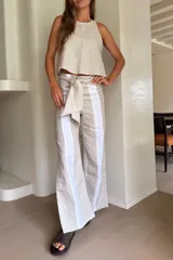Pantalón de lino de pierna ancha, color beige con franjas verticales blancas a los lados y lazo ajustable en la cintura.