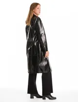 Chaqueta larga tipo trench de charol negro con acabado brillante e impermeable. Presenta cuello con solapa, cierre frontal con botones metálicos plateados y bolsillos laterales. Su diseño es de corte recto y estructura rígida.