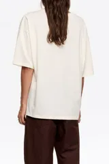 Remera de corte oversize color gris oscuro con efecto lavado, cuello redondo y manga corta amplia. Presenta un estampado pequeño de un perro salchicha con el logo de la marca en el pecho.
