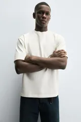 Camiseta de manga corta y cuello redondo, color blanco roto, con textura seersucker.