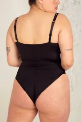Body colaless negro con puntilla blanca y breteles regulables transparentes. Tiene ganchos reforzados en la parte delantera y broches en la entrepierna con fundillo de algodón.