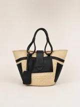 Bolso tipo tote confeccionado en rafia natural con detalles de cuero negro, asas superiores y un bolsillo frontal con solapa.