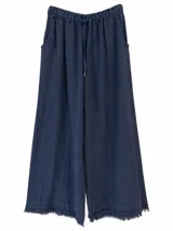 Pantalón ancho color azul marino con cintura elástica ajustable mediante cordón y detalles de flecos en los dobladillos.